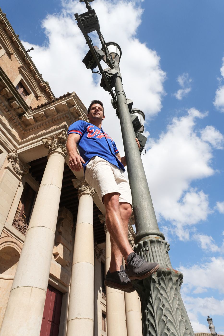 Alex hanging one-handed from a lamppost
